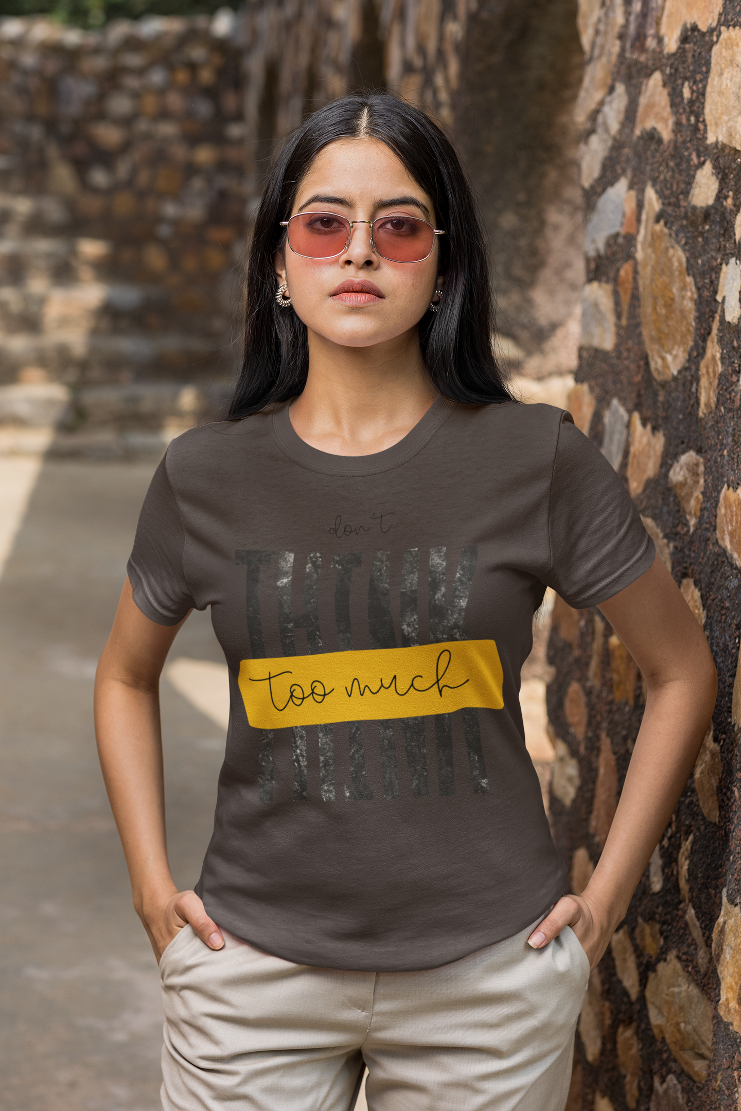 Woman wearing a Charcoal Grey t-shirt with text standing against a stone wall.