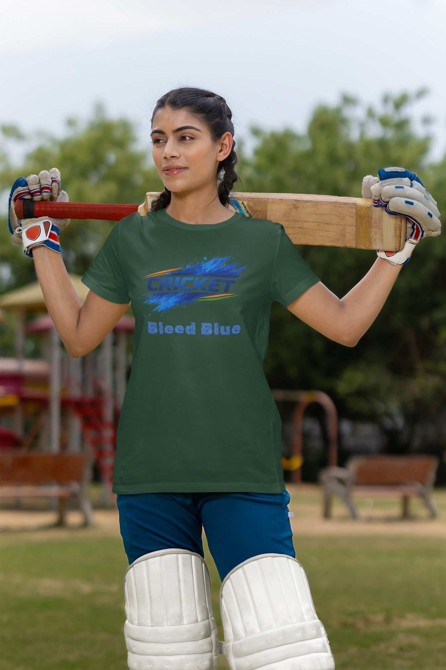 Woman holding a cricket bat with a olive green t-shirt in an outdoor