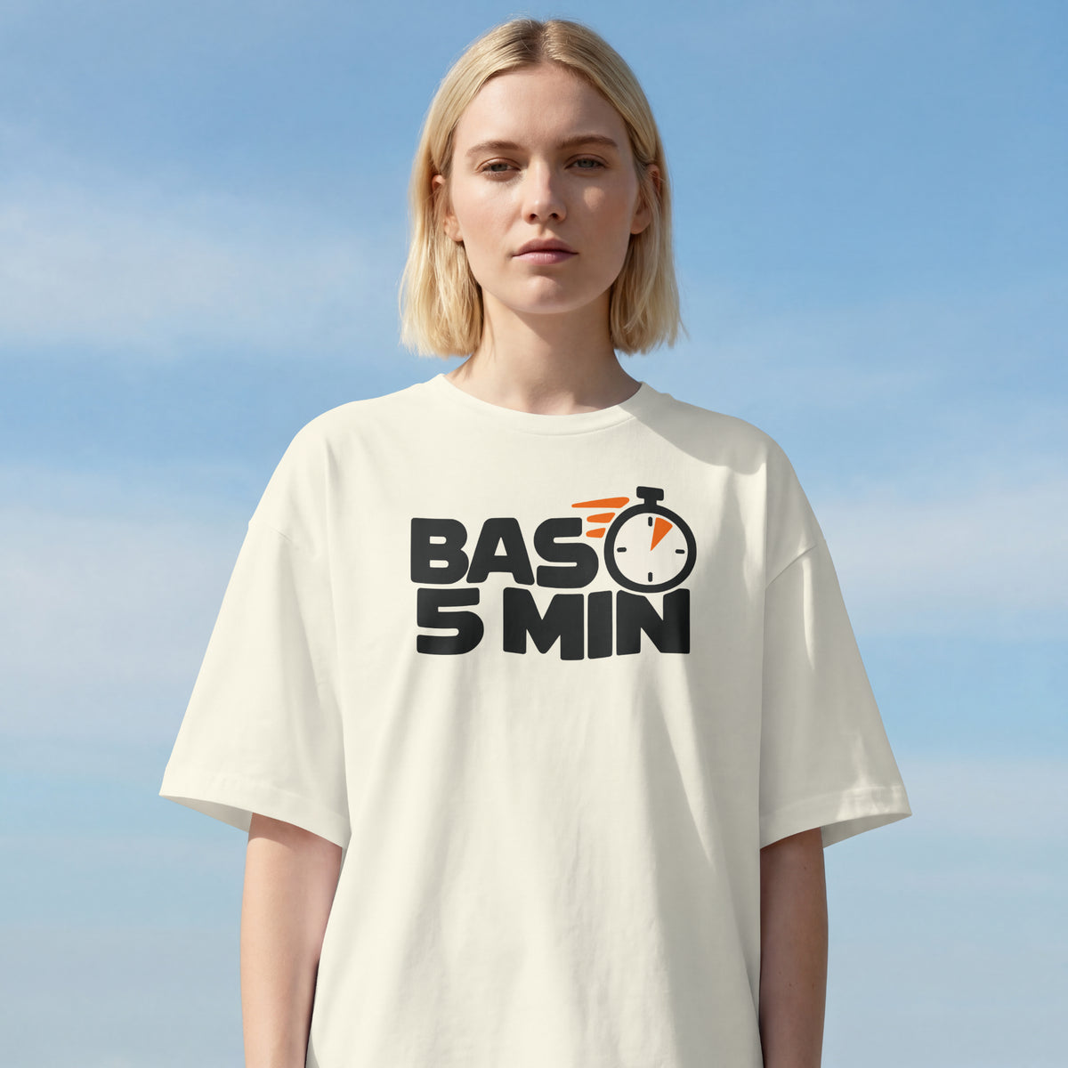 Woman wearing the Off White Bas 5 Min oversized t-shirt against a clear sky, bold BAS 5 MIN lettering on the front