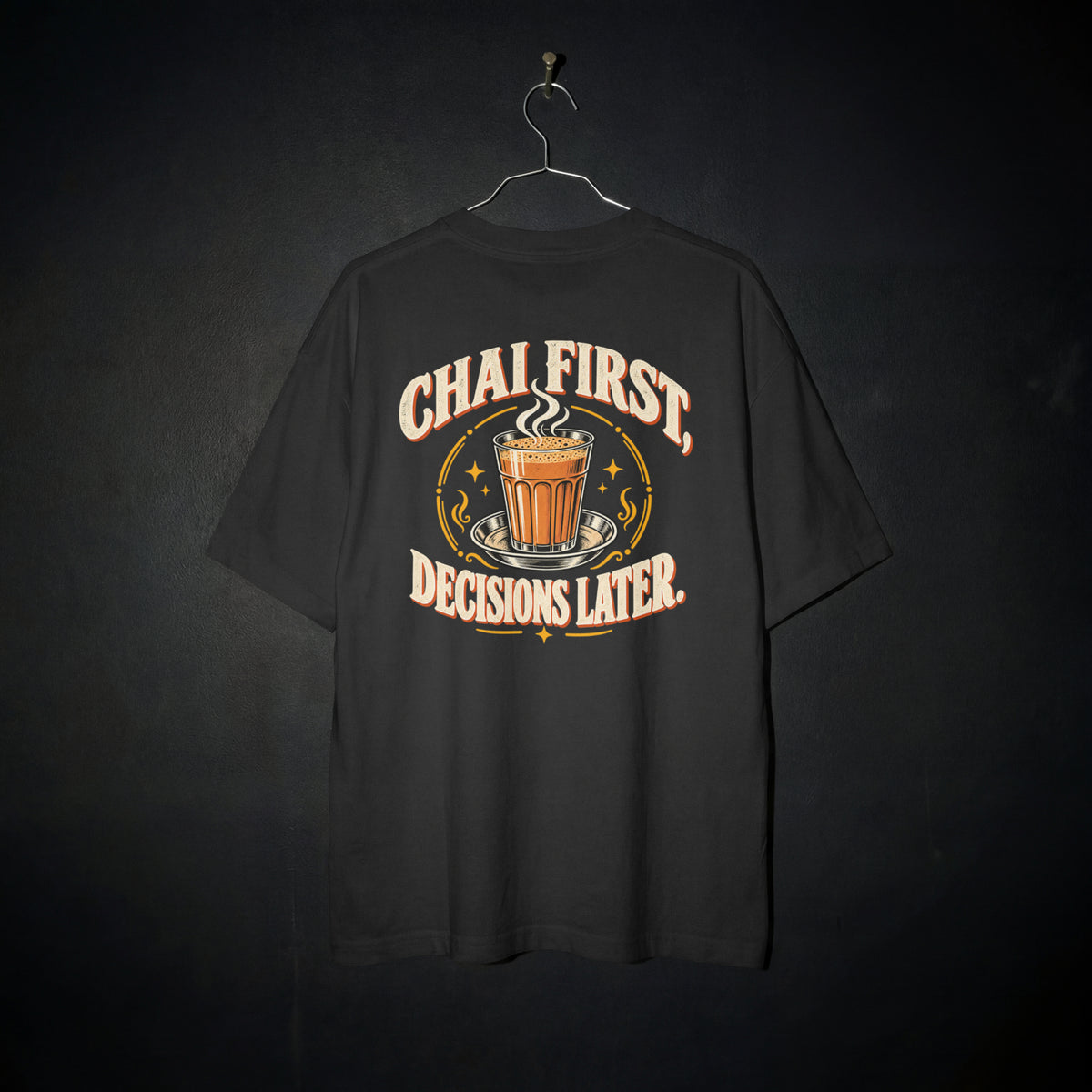 Black Chai First Decisions Later oversized T-shirt on a hanger against a dark backdrop, front view of the cutting chai graphic print