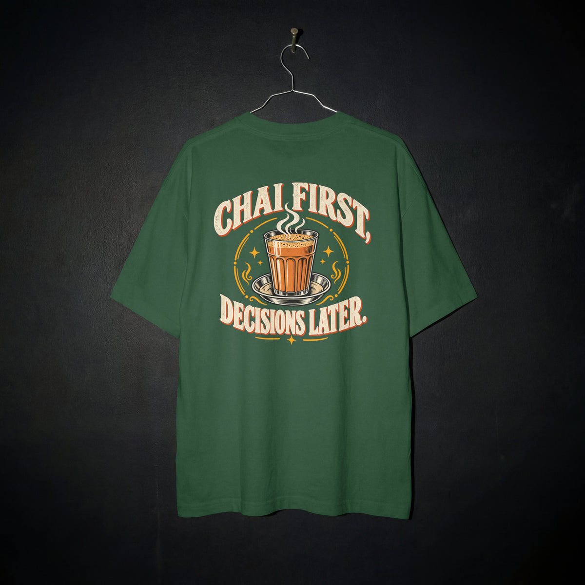 Bottle Green Chai First Decisions Later oversized T-shirt on a hanger against a dark backdrop, front view of the cutting chai graphic print
