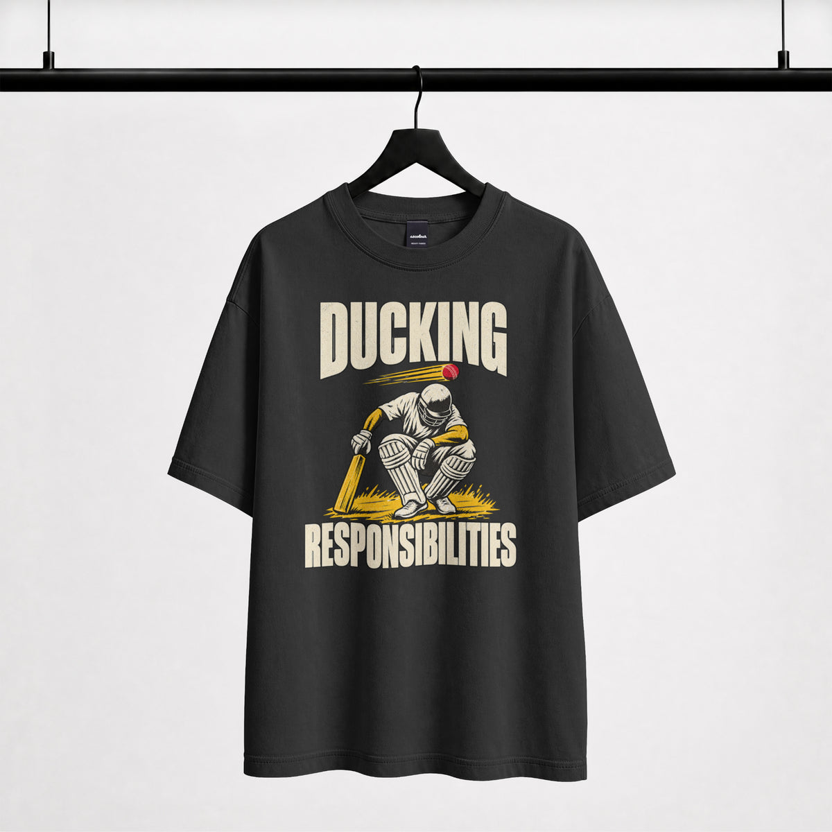 Black Ducking Responsibilities oversized T-shirt on a hanger, front print of a helmeted cricket batter ducking a red ball