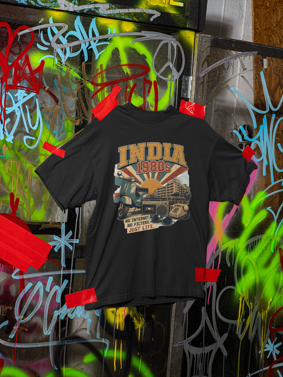 India 80s retro oversized t-shirt in Black taped to a graffiti wall – full front print view