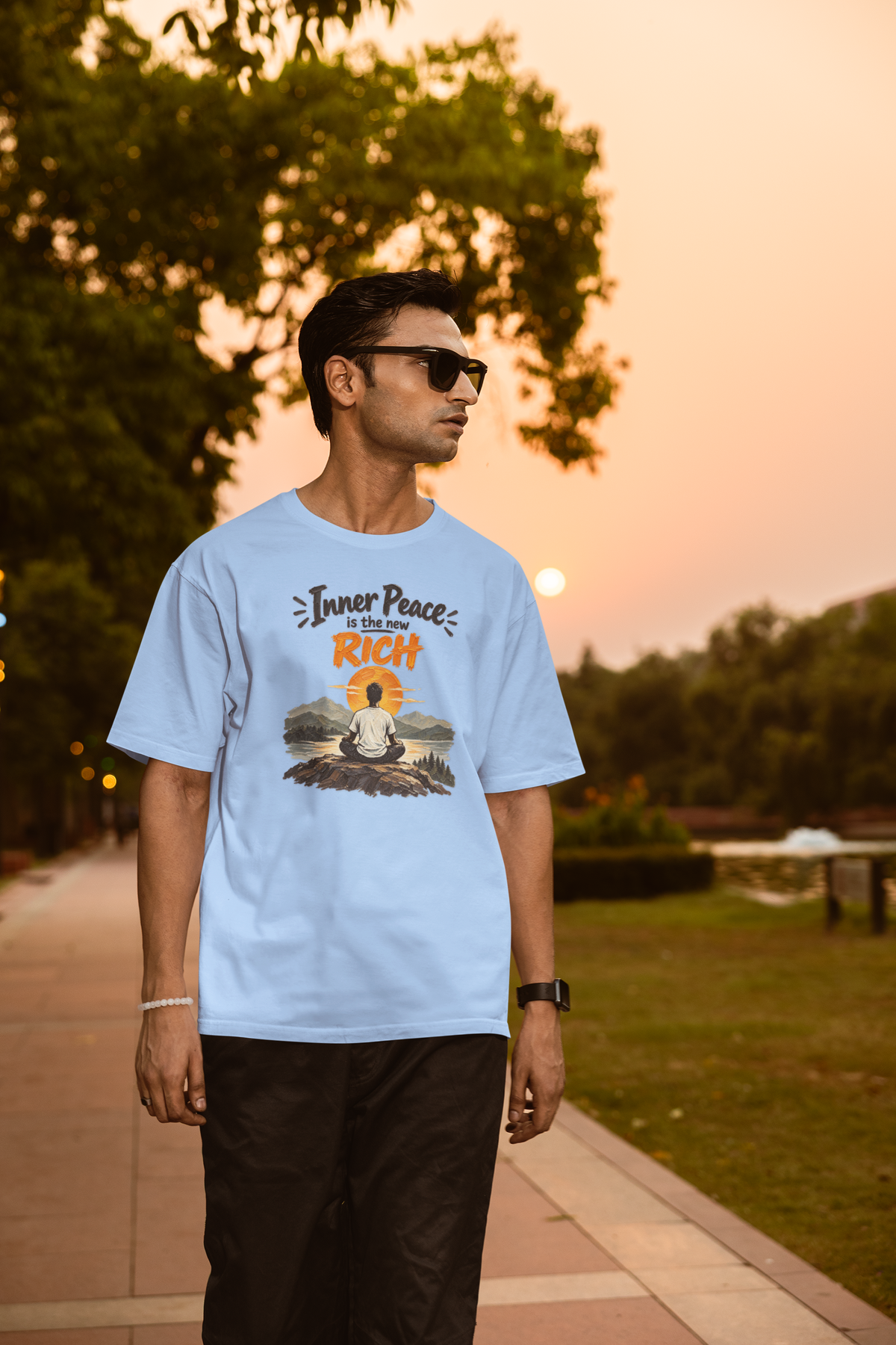 Baby Blue Inner Peace Is The New Rich meditation unisex oversized t-shirt worn by a man at sunset, front view