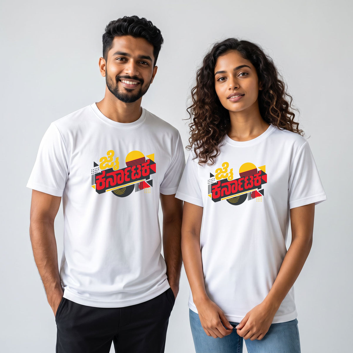 Man and woman wearing the white Nauma Jai Karnataka retro jersey T-shirt with red and yellow Kannada lettering, a striped sunset and geometric shapes, styled with black trousers and blue jeans