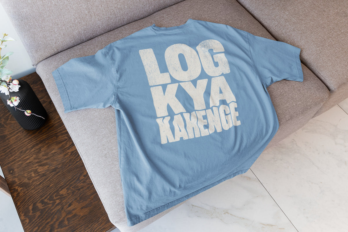 Baby Blue Log Kya Kahenge oversized t-shirt laid flat on a sofa, showing the stacked distressed cream lettering front print
