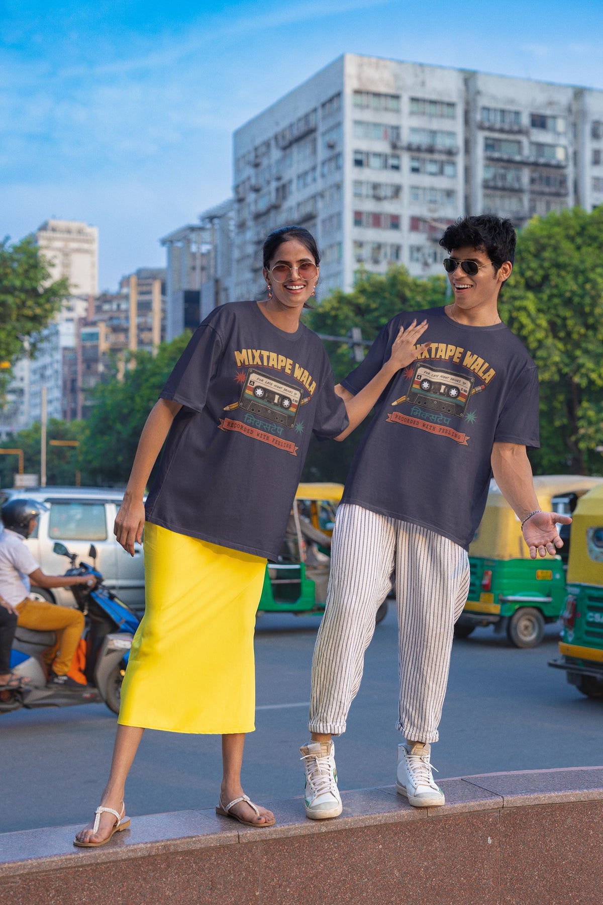 Man and woman wearing the Navy Blue Mixtape Wala oversized t-shirt on a city street with auto-rickshaws