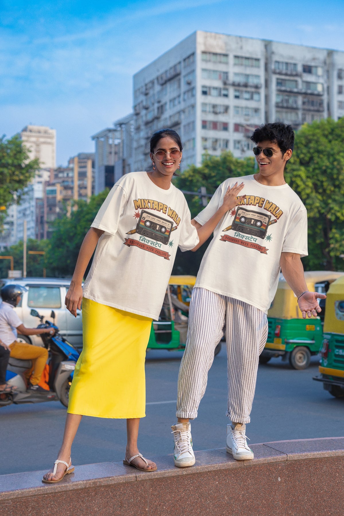 Man and woman wearing the Off white Mixtape Wala oversized t-shirt on a city street with auto-rickshaws