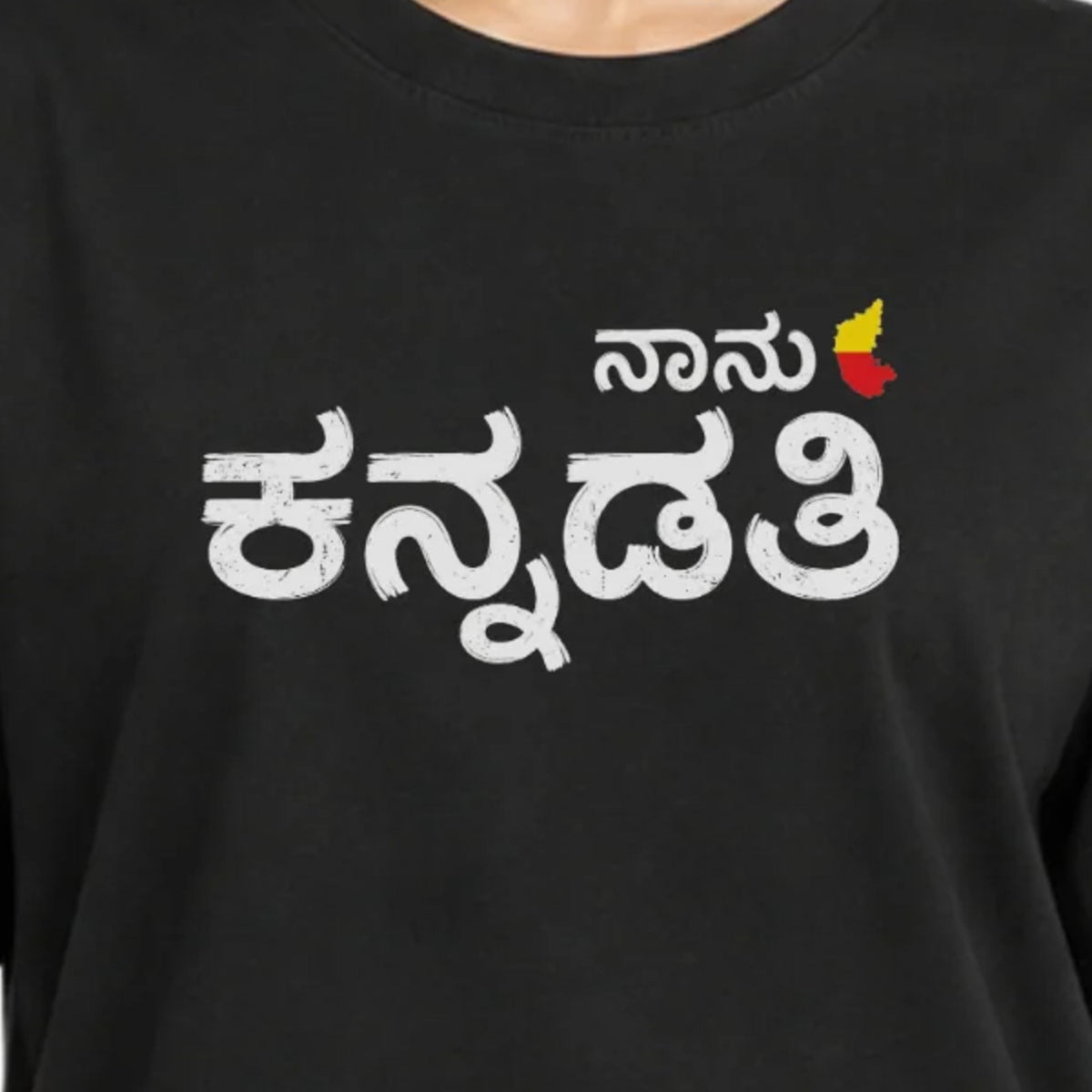 Close-up of the ನಾನು ಕನ್ನಡತಿ print worn on a black women's T-shirt, showing the white Kannada lettering, red and yellow Karnataka map and crew neckline