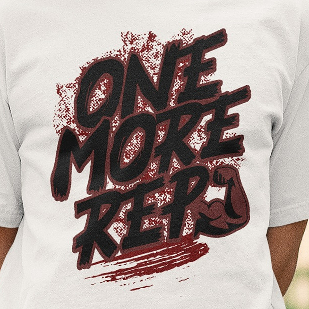 Close-up of the One More Rep brush lettering and flexed arm print on the white Nauma oversized T-shirt
