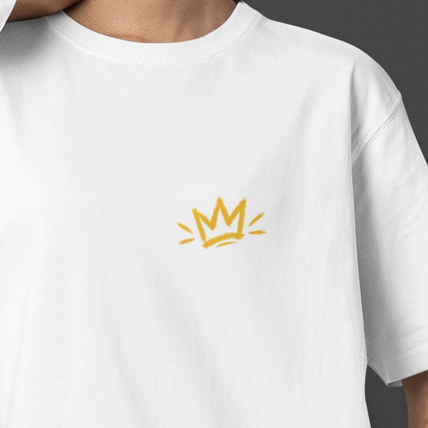 White Unfortunately Money Is Everything oversized T-shirt front close-up – small mustard yellow crown print on the left chest