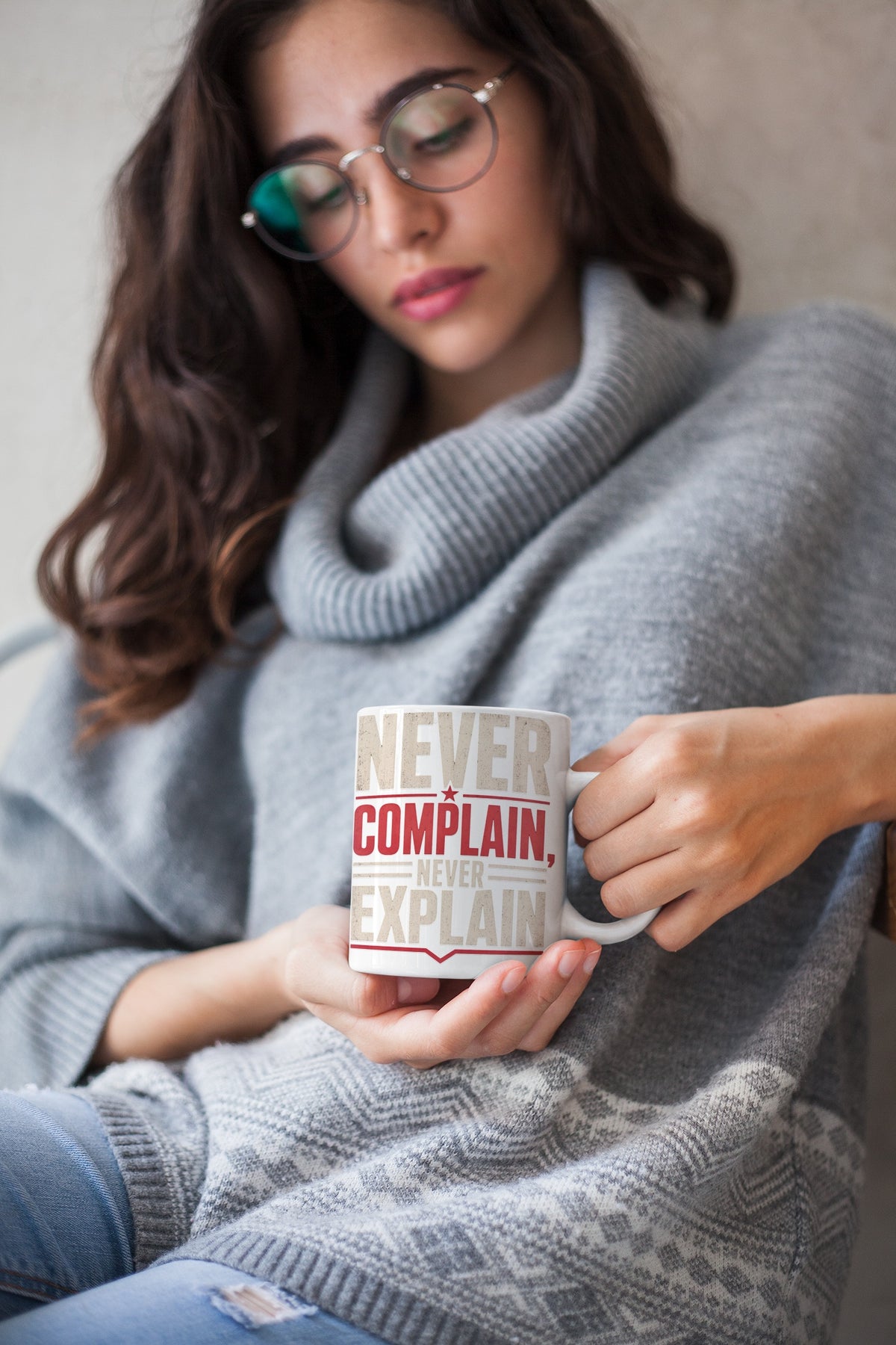 Woman in a winter sweater holding the Never Complain Never Explain 11oz ceramic coffee mug by Nauma