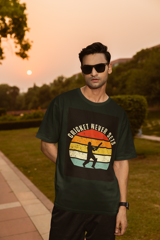 Man wearing a bottle green t-shirt with 'Cricket Never Sleeps' design outdoors during sunset.