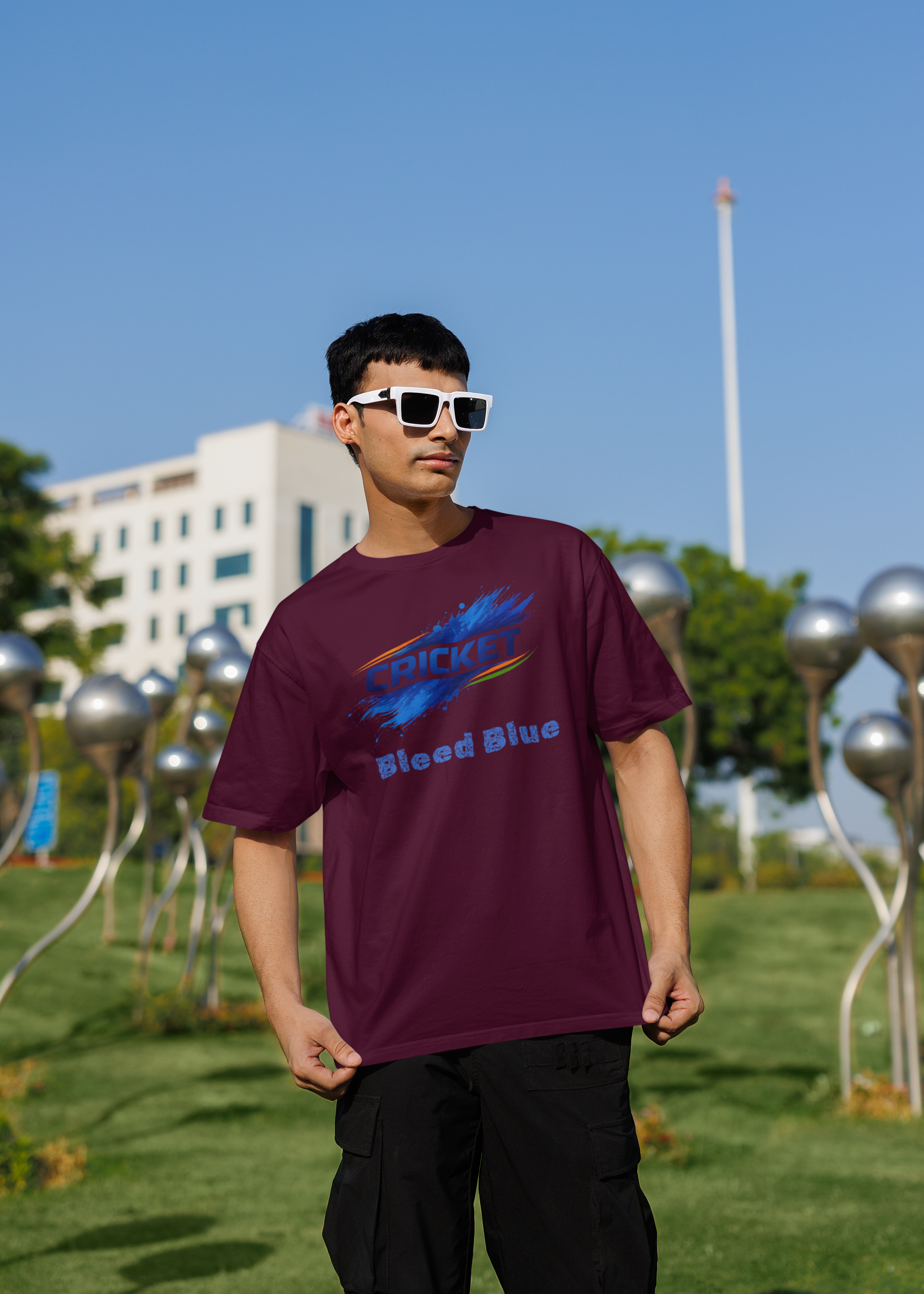 Person wearing a burgundy t-shirt with a colorful graphic design outdoors on a sunny day.