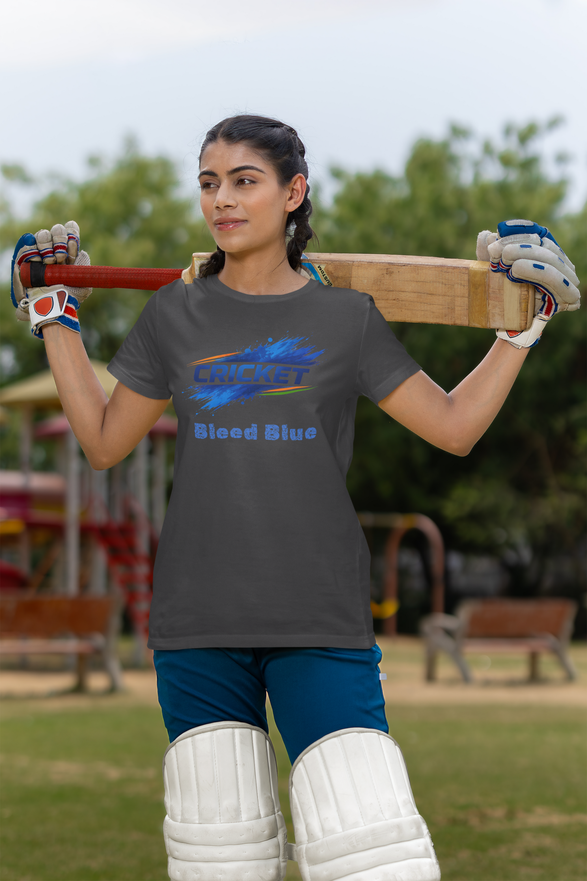 Woman holding a cricket bat with a charcoal grey t-shirt in an outdoor setting