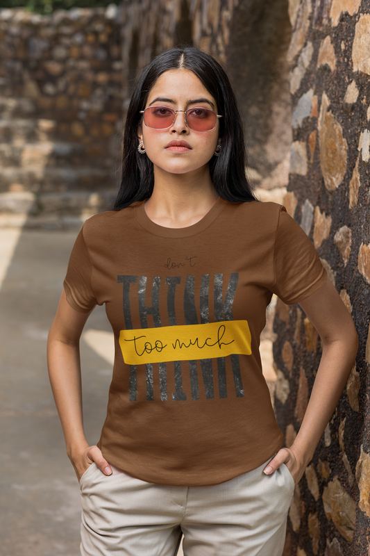Woman wearing a Coffee Brown t-shirt with text standing against a stone wall.