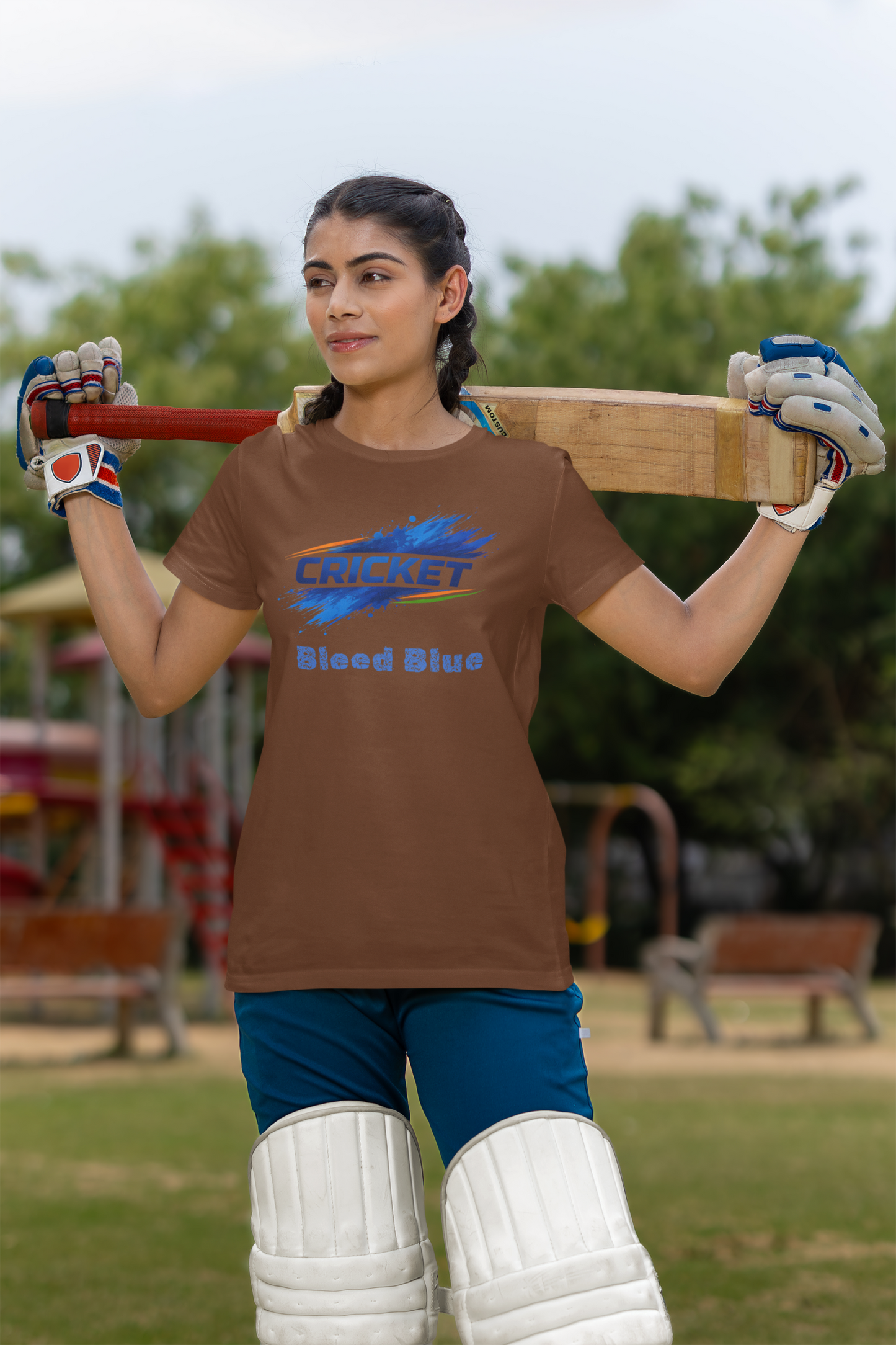 Woman holding a cricket bat with a coffee brown t-shirt in an outdoor 