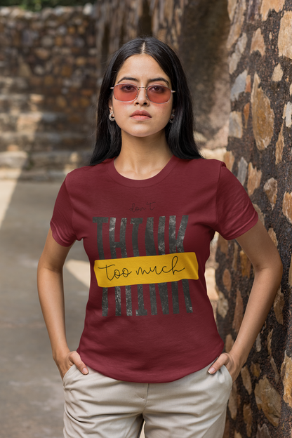 Woman wearing a Maroon t-shirt with text standing against a stone wall.