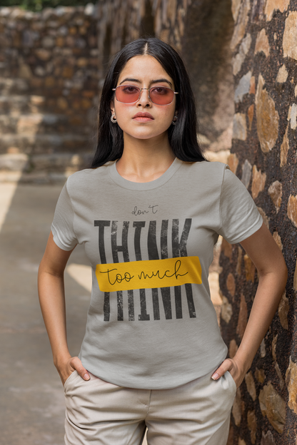 Woman wearing a Melange Grey t-shirt with text standing against a stone wall.