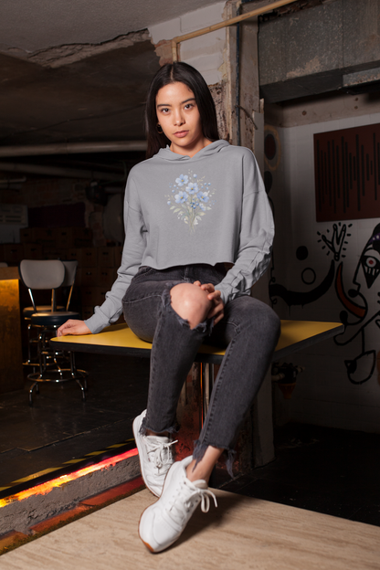 Woman wearing a Melange grey hoodie with floral design sitting on a bench in an urban setting.
