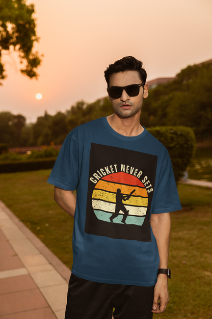 Man wearing a navy blue t-shirt with 'Cricket Never Sleeps' design outdoors during sunset.