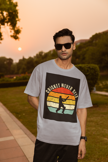 Man wearing a silver frost t-shirt with 'Cricket Never Sleeps' design outdoors during sunset.