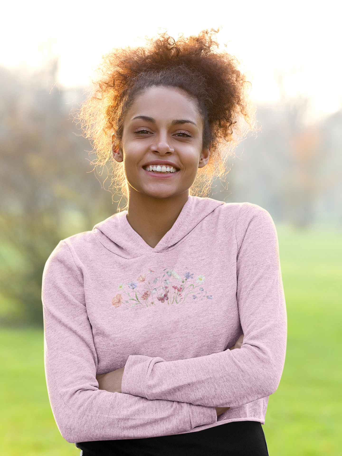 Woman wearing a light pink hoodie with floral design outdoors