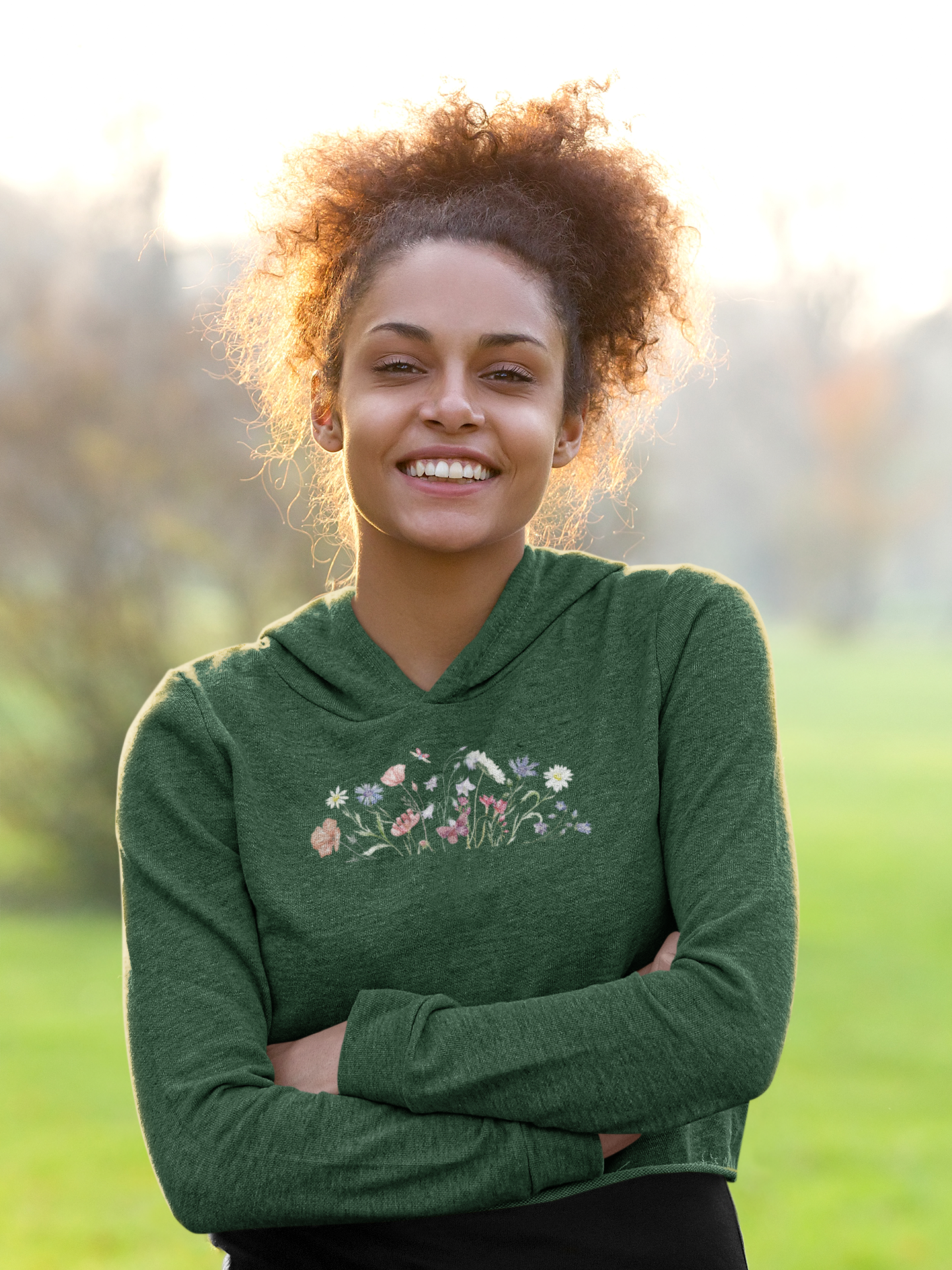 Woman wearing a olive green hoodie with floral design outdoors