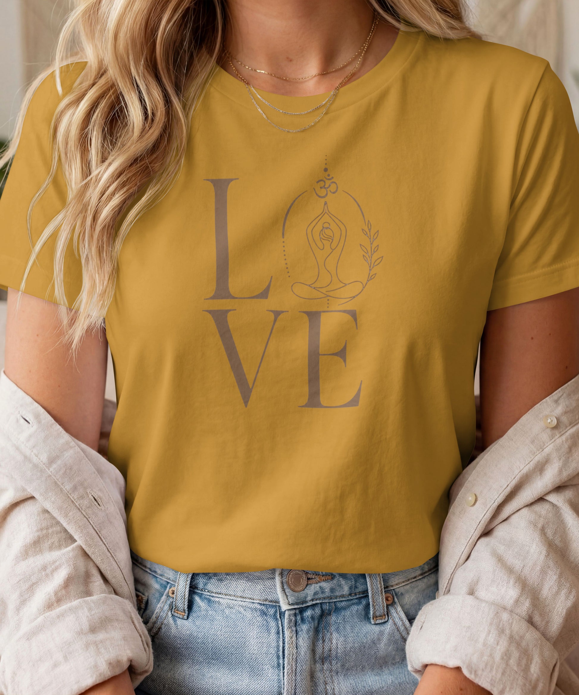 A woman modelling a mustard yellow graphic t-shirt featuring a minimalist "LOVE" design with a meditating yoga pose and an Om symbol