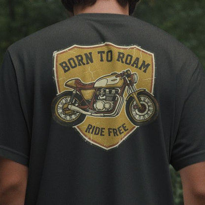 Close-up of the Born To Roam back print on a black oversized t-shirt, showing the distressed mustard shield badge and vintage cafe racer motorcycle artwork