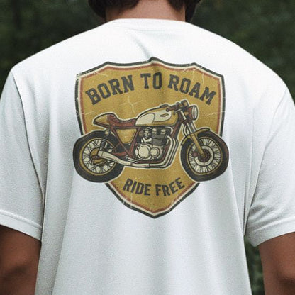 Close-up of the Born To Roam cafe racer badge on a white oversized t-shirt, showing the Ride Free banner and cracked vintage print texture