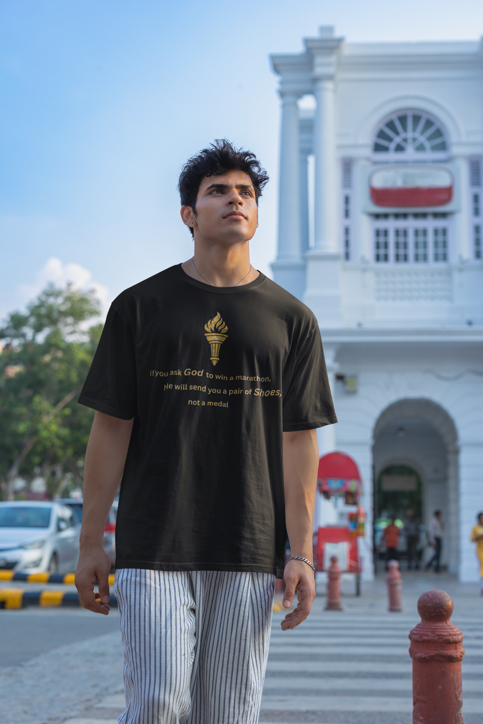 Front view of a Black unisex oversized t-shirt featuring a golden torch graphic and motivational quote about winning a marathon.