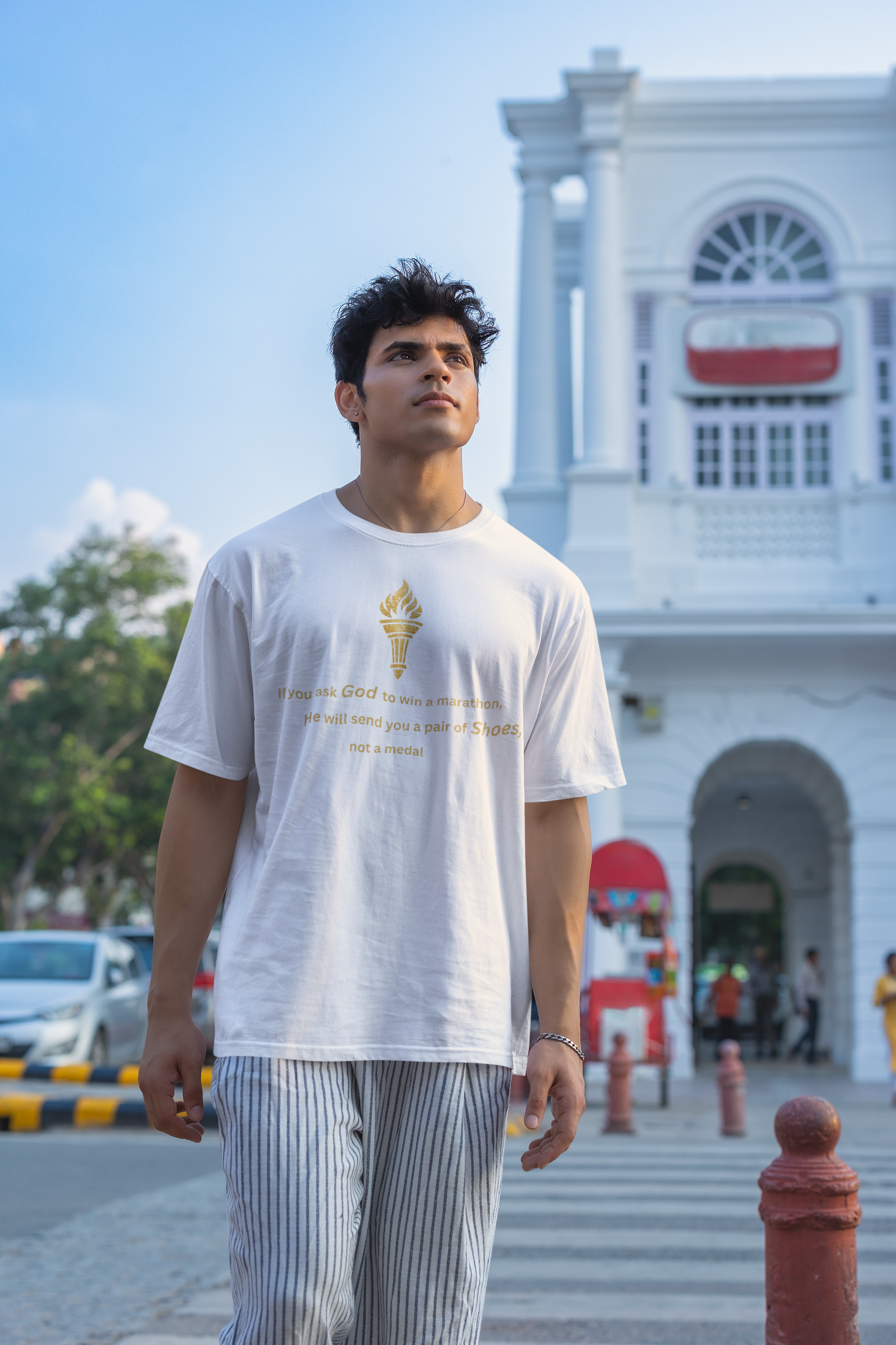 Minimalist White oversized streetwear t-shirt with a vintage golden torch print and "God and Marathon" inspirational text.