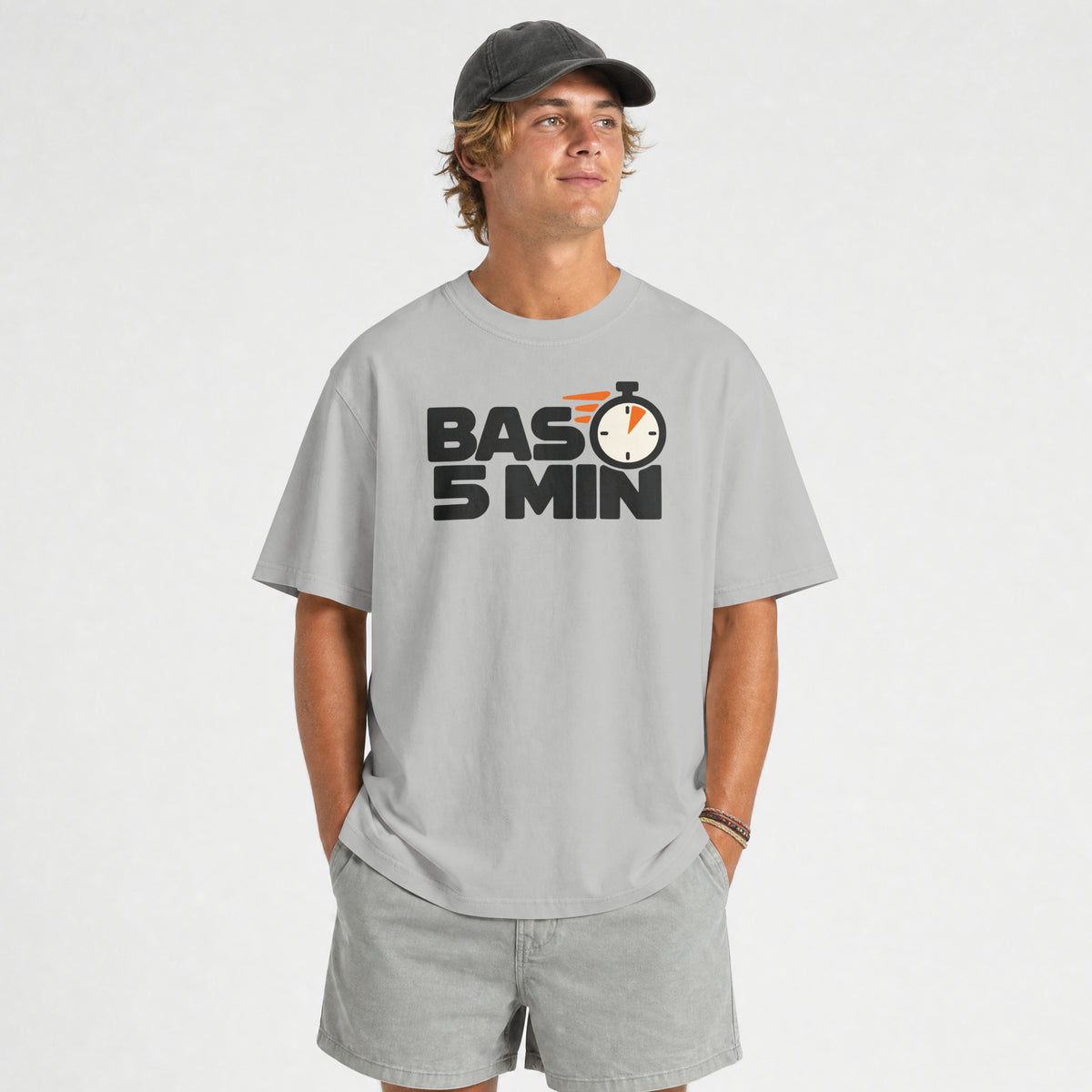 Man in a dark cap wearing the Melange Grey Bas 5 Min unisex oversized t-shirt, front view of the stopwatch print