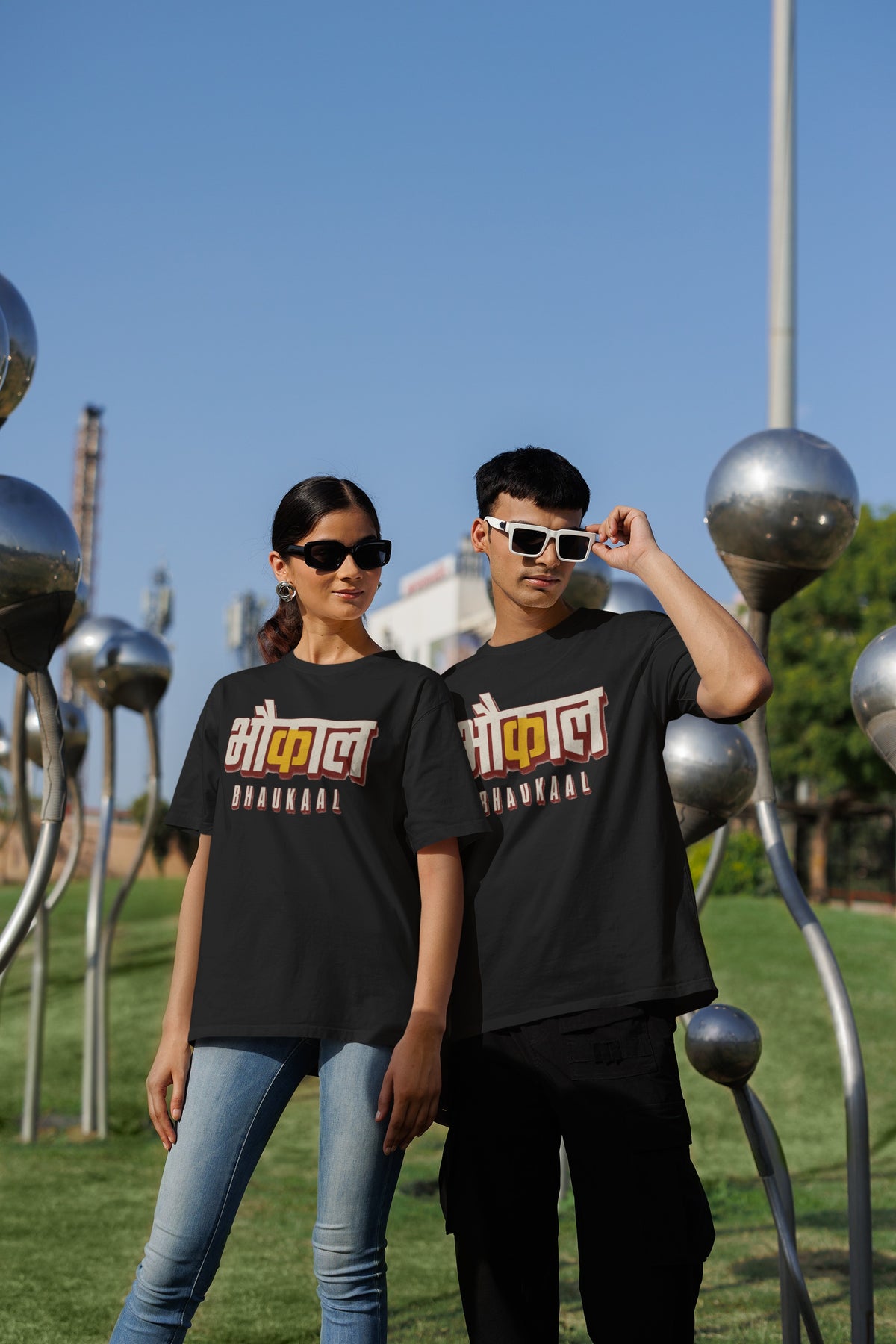 Black Bhaukaal oversized t-shirt worn by a man and a woman outdoors, Hindi typography print across the chest