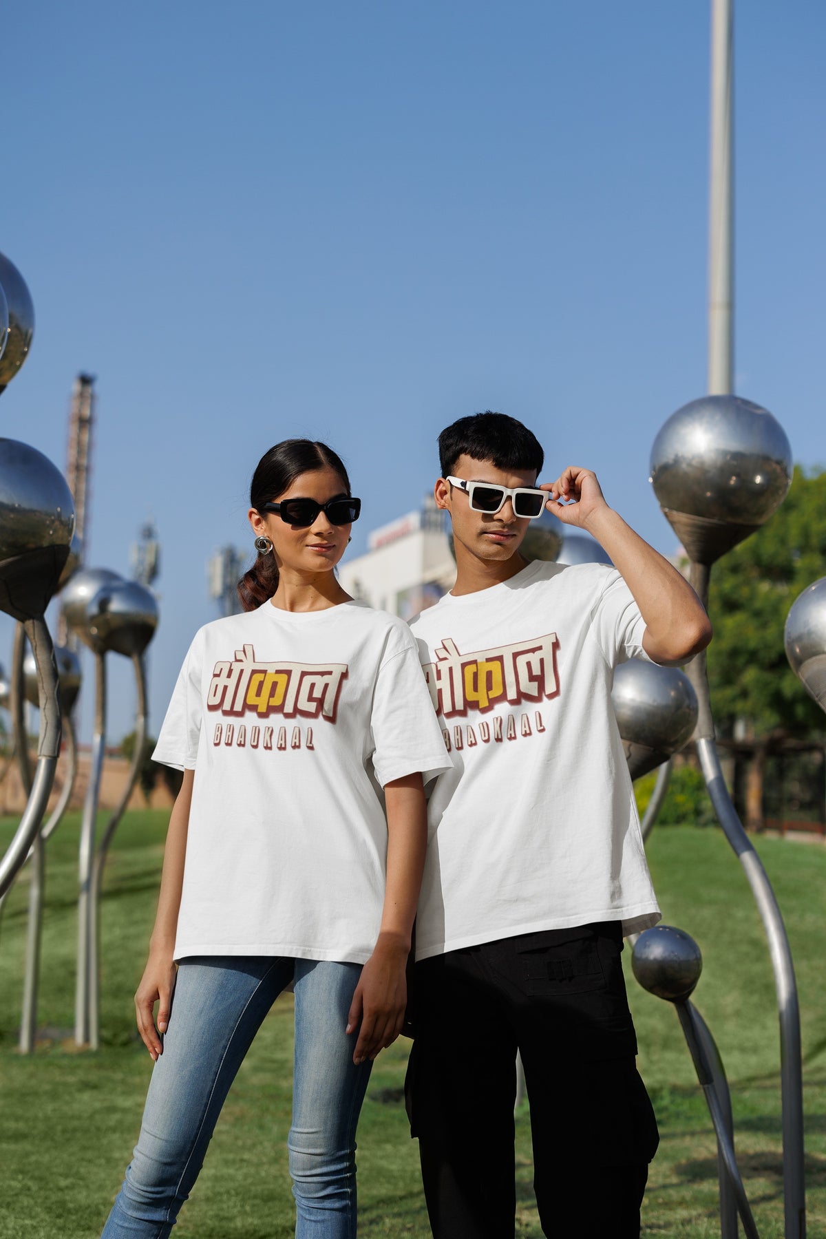 White Bhaukaal oversized t-shirt worn by a man and a woman outdoors, Hindi typography print across the chest
