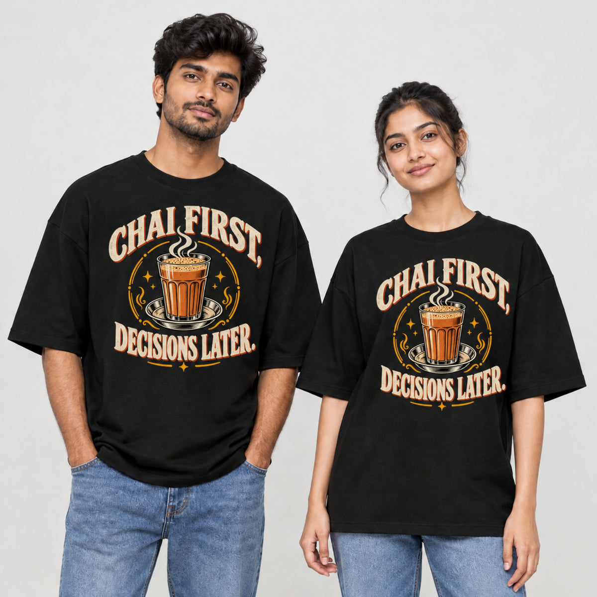 Black Chai First Decisions Later unisex oversized T-shirt worn by a man and a woman, front print with a cutting chai glass and retro cream lettering