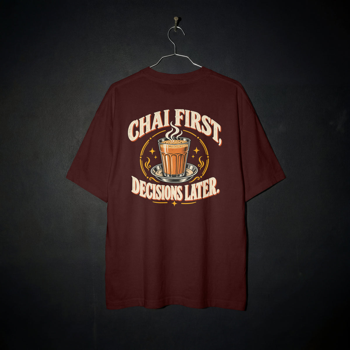 Maroon Chai First Decisions Later oversized T-shirt on a hanger against a dark backdrop, front view of the cutting chai graphic print