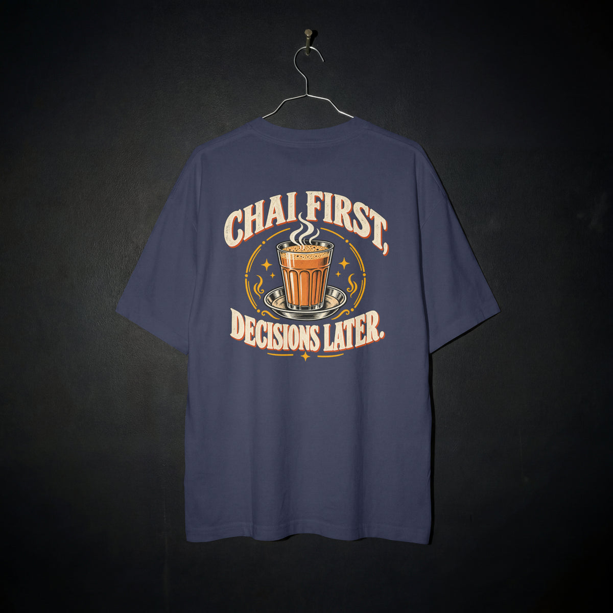 Navy Blue Chai First Decisions Later oversized T-shirt on a hanger against a dark backdrop, front view of the cutting chai graphic print