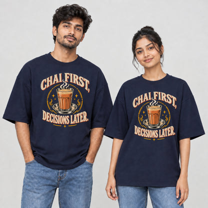 Navy Blue Chai First Decisions Later unisex oversized T-shirt worn by a man and a woman, front print with a cutting chai glass and retro cream lettering