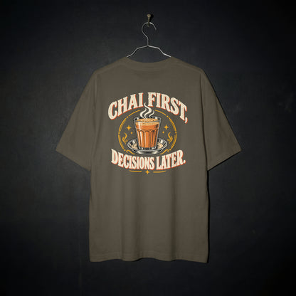 Olive Green Chai First Decisions Later oversized T-shirt on a hanger against a dark backdrop, front view of the cutting chai graphic print