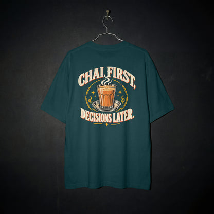 Petrol Blue Chai First Decisions Later oversized T-shirt on a hanger against a dark backdrop, front view of the cutting chai graphic print