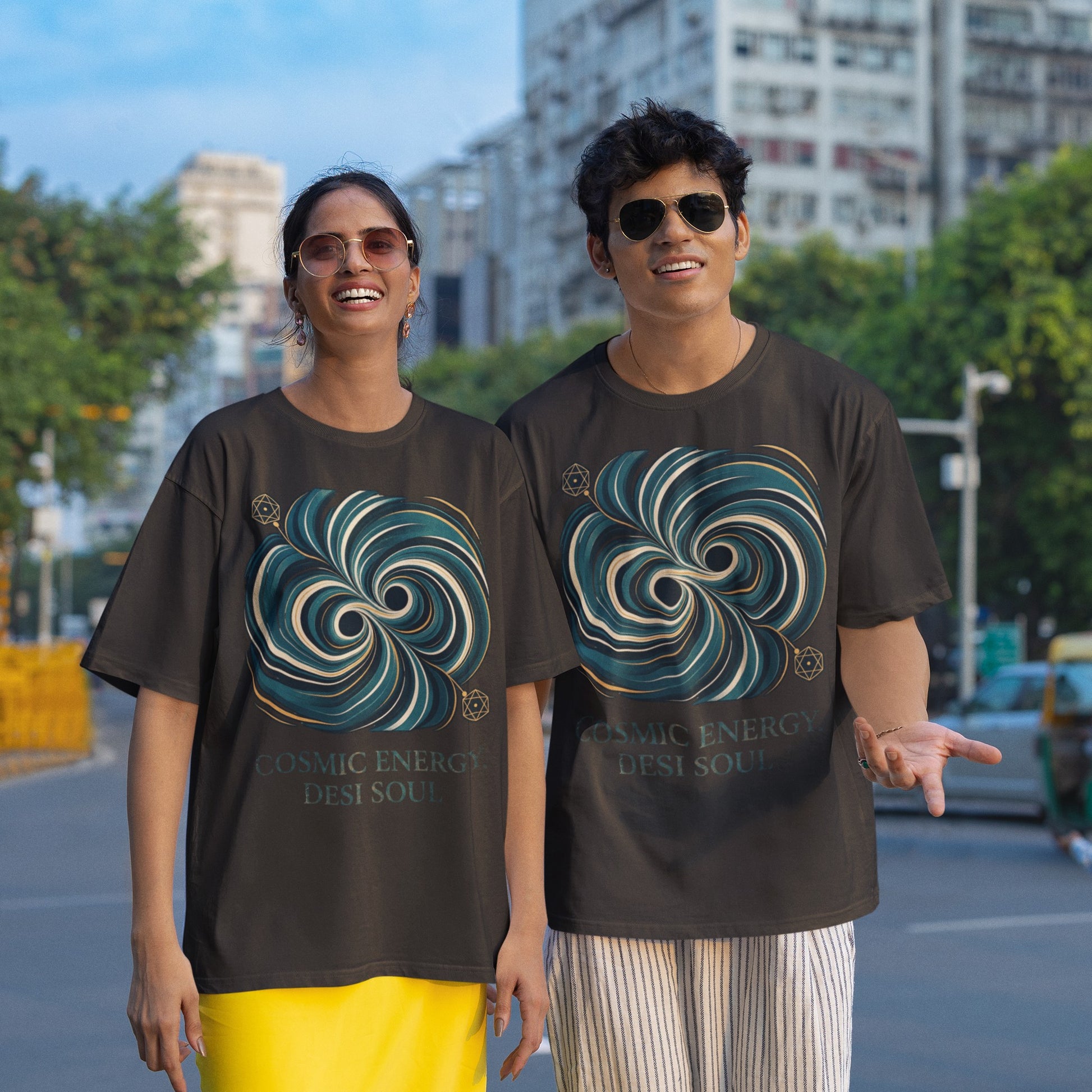 Two models wearing black Nauma oversized t-shirts with a teal and gold colliding black holes print
