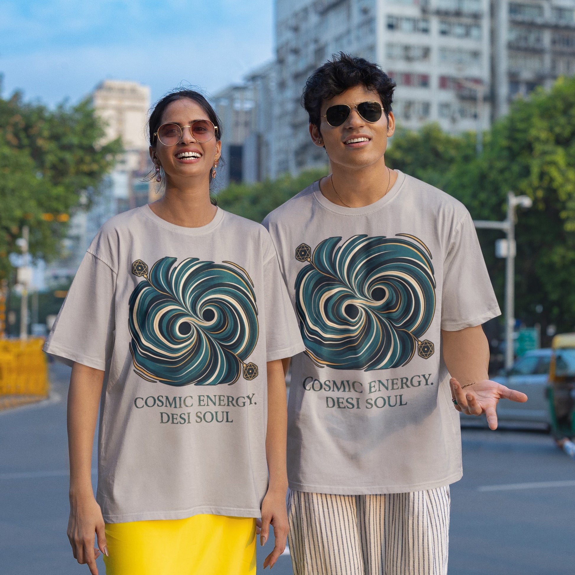 Two models wearing melange grey Nauma oversized t-shirts with a teal and gold colliding black holes print