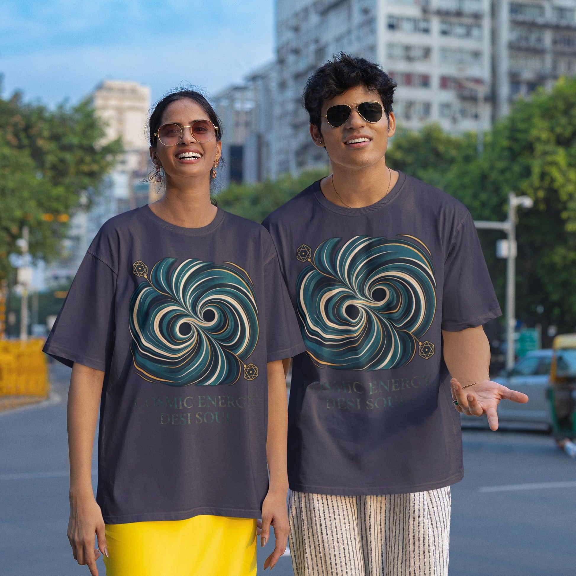 Two models wearing navy blue Nauma oversized t-shirts with a teal and gold colliding black holes print