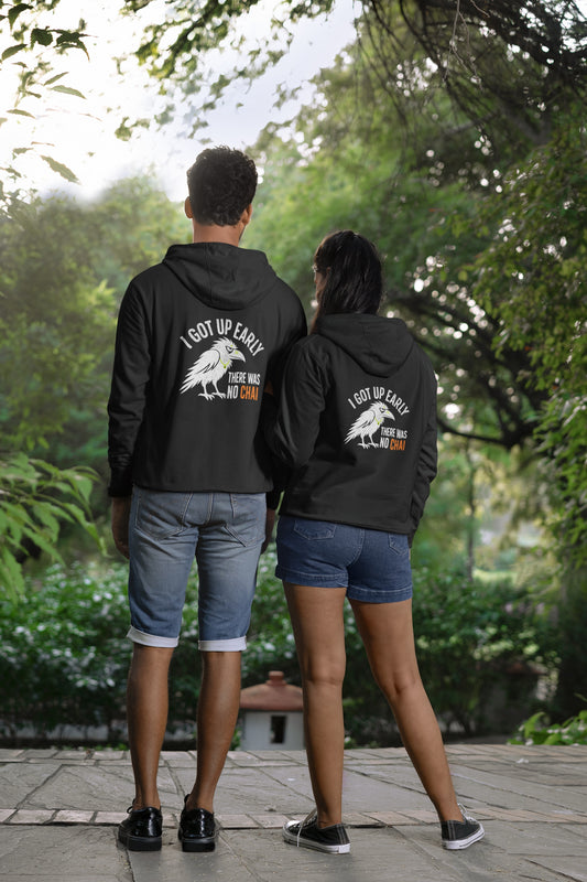 Black unisex hoodie with white crow and no chai slogan back print, worn by a couple seen from behind