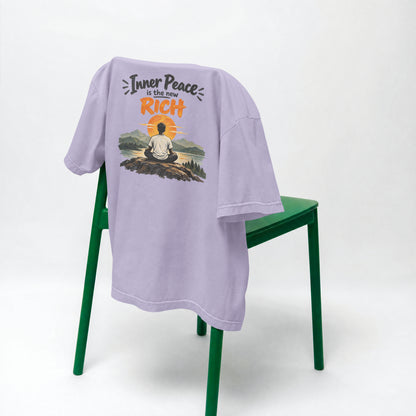 Lavender Inner Peace Is The New Rich oversized t-shirt draped over a green chair, showing the front print