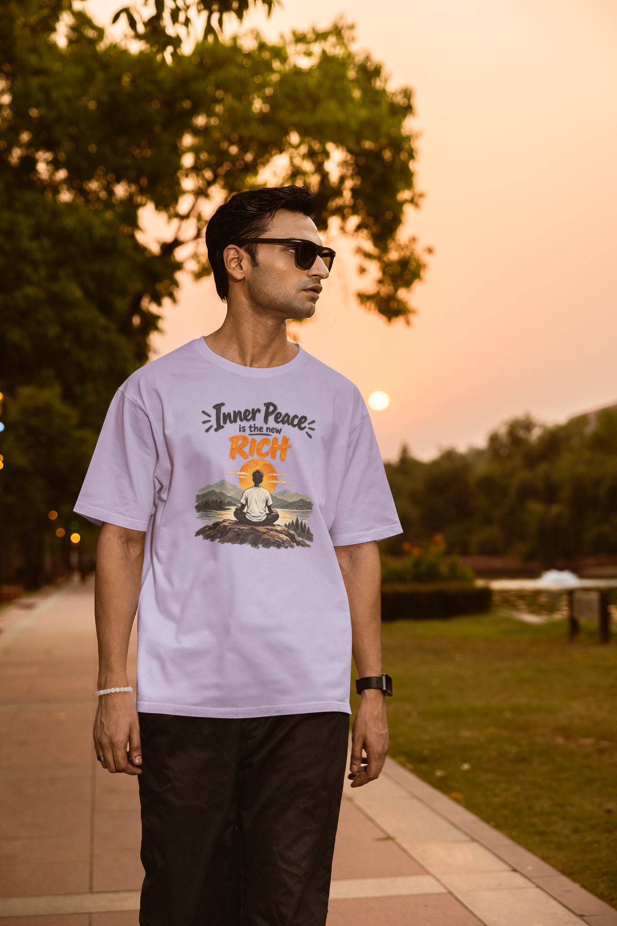 Lavender Inner Peace Is The New Rich meditation unisex oversized t-shirt worn by a man at sunset, front view