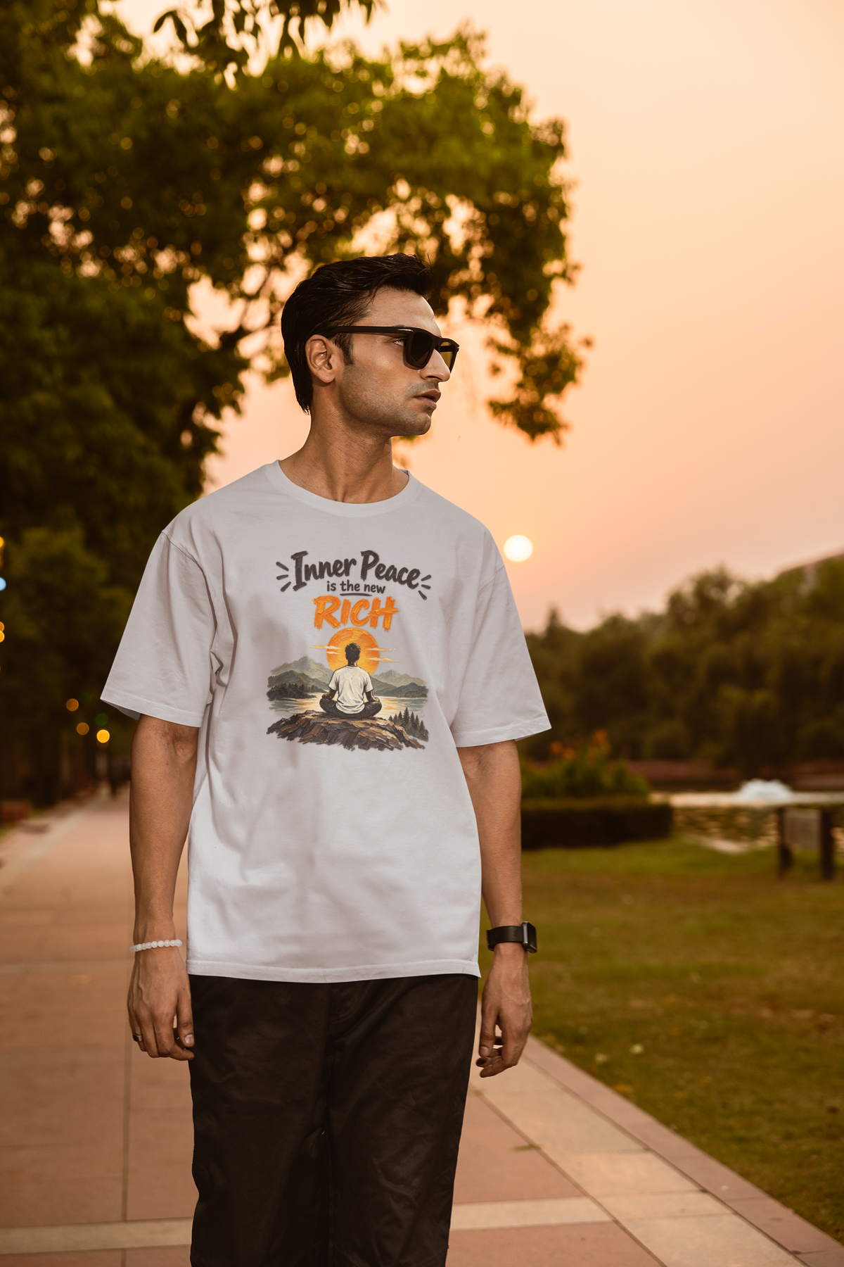 Melange Grey Inner Peace Is The New Rich meditation unisex oversized t-shirt worn by a man at sunset, front view