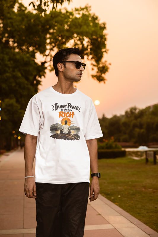 White Inner Peace Is The New Rich meditation unisex oversized t-shirt worn by a man at sunset, front view